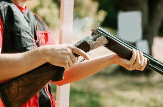 man opens the shotgun bolt after one shot with smoke